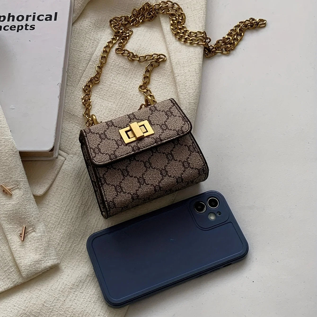 The Mini - Compact Women's Mini Handbag in brown pattern with chain strap beside a smartphone.